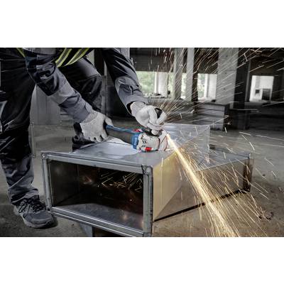 'Person grinding metal pipe with angle grinder, sparks flying. Construction environment with concrete walls in the background.'