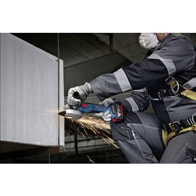 A person in workwear is cutting metal with an angle grinder, with sparks flying. Protective clothing includes gloves and a mask.