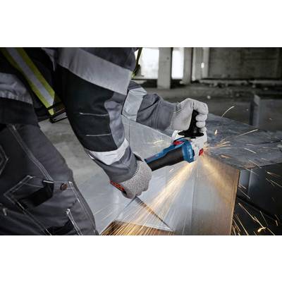 A person is cutting metal with a blue angle grinder, with sparks flying. They are wearing protective clothing and gloves.