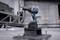 A cordless drill sits on a metal block in an industrial setting, surrounded by screws and metal structures.