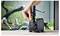 'A hand adjusts a knob on a black water pump positioned in front of a fish tank with green plants and aquarium decorations.'