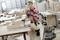A man is sanding wood in a workshop using an electric sander. A vacuum cleaner is standing nearby.