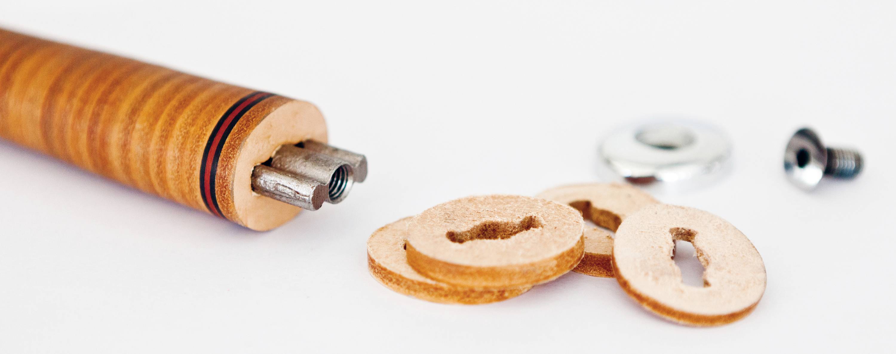 Leather punch with three round pieces of leather, a metal screw component, and a washer, set against a white background.