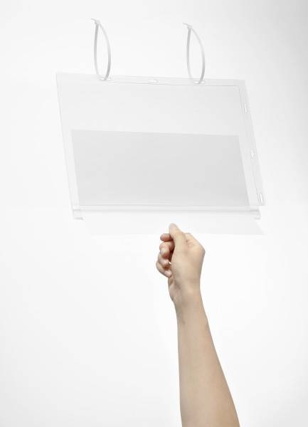 A hand is holding a transparent, empty plastic folder. The folder has two rings for hanging. The background is a neutral white.