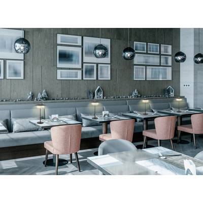 Modern restaurant interior with pink chairs, wooden tables, and ambient lighting. Wall art and soft tones create a cozy atmosphere.