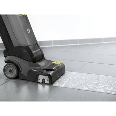 A floor cleaning device is cleaning a tiled surface with soapy water. The floor appears half clean and half dirty.