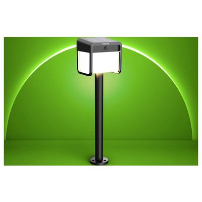 A black Philips outdoor lamp post light with square illuminated panels on a tall pole against a green background.