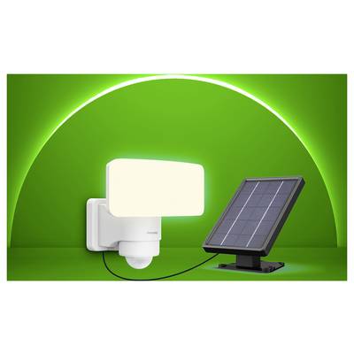 Solar-powered motion sensor security light with attached panel on a green background.