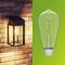 On the left, a wall-mounted light fixture on a brick wall, on the right an energy-saving light bulb against a green background.
