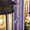 Solar lamp with warm light on a terrace at dusk. The lamp has a modern design with visible filament.