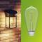Links: A wall light on a brick wall. Right: A light bulb on a green background. Both are shining brightly.