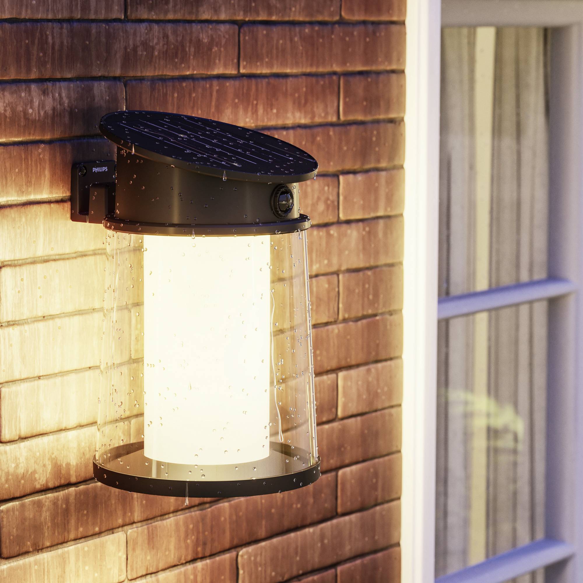 Outdoor solar-powered lantern mounted on a brick wall, illuminated at dusk, with a curtained window beside it.