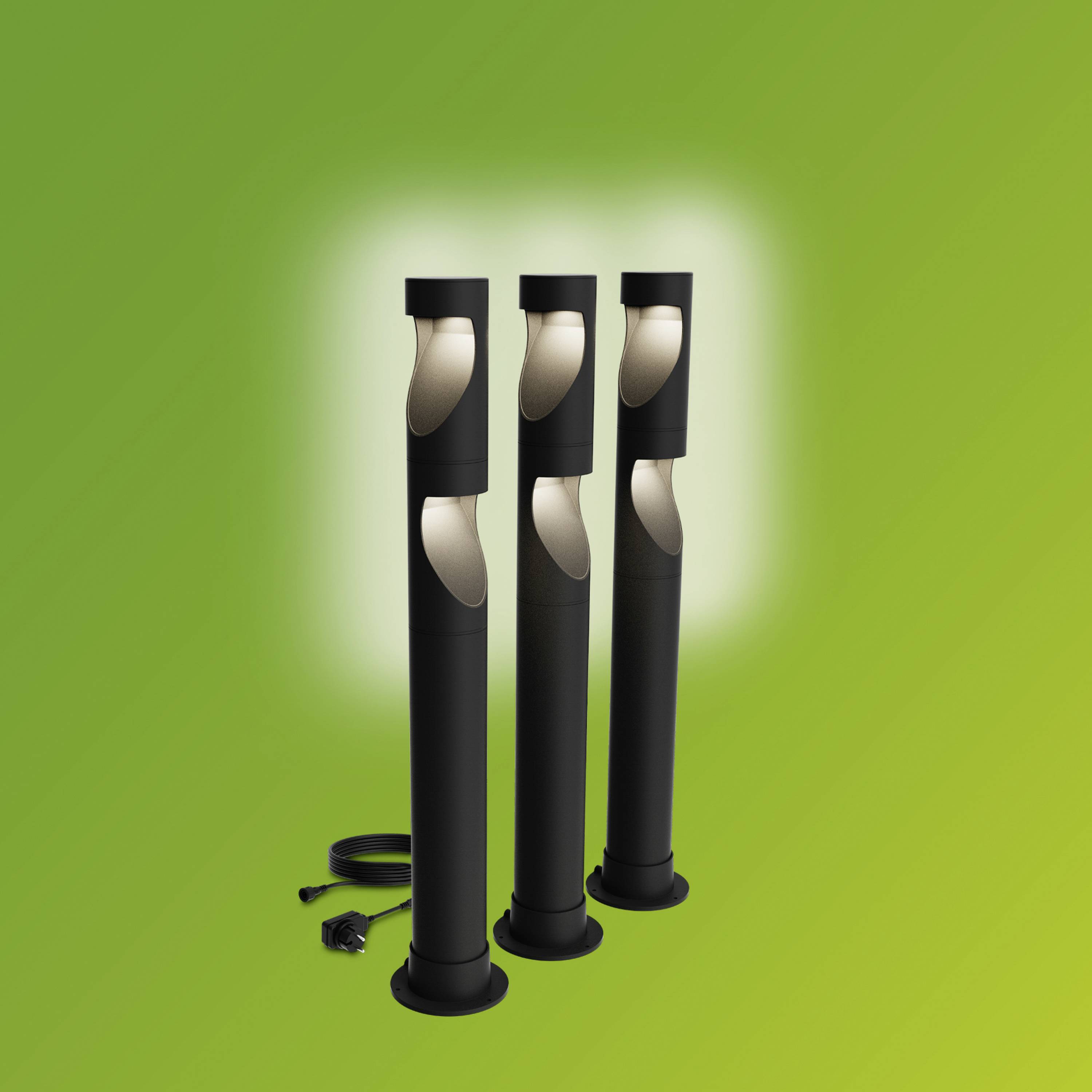 Three modern, black garden lamps on a green background, standing side by side, with visible cable connections at the bottom.