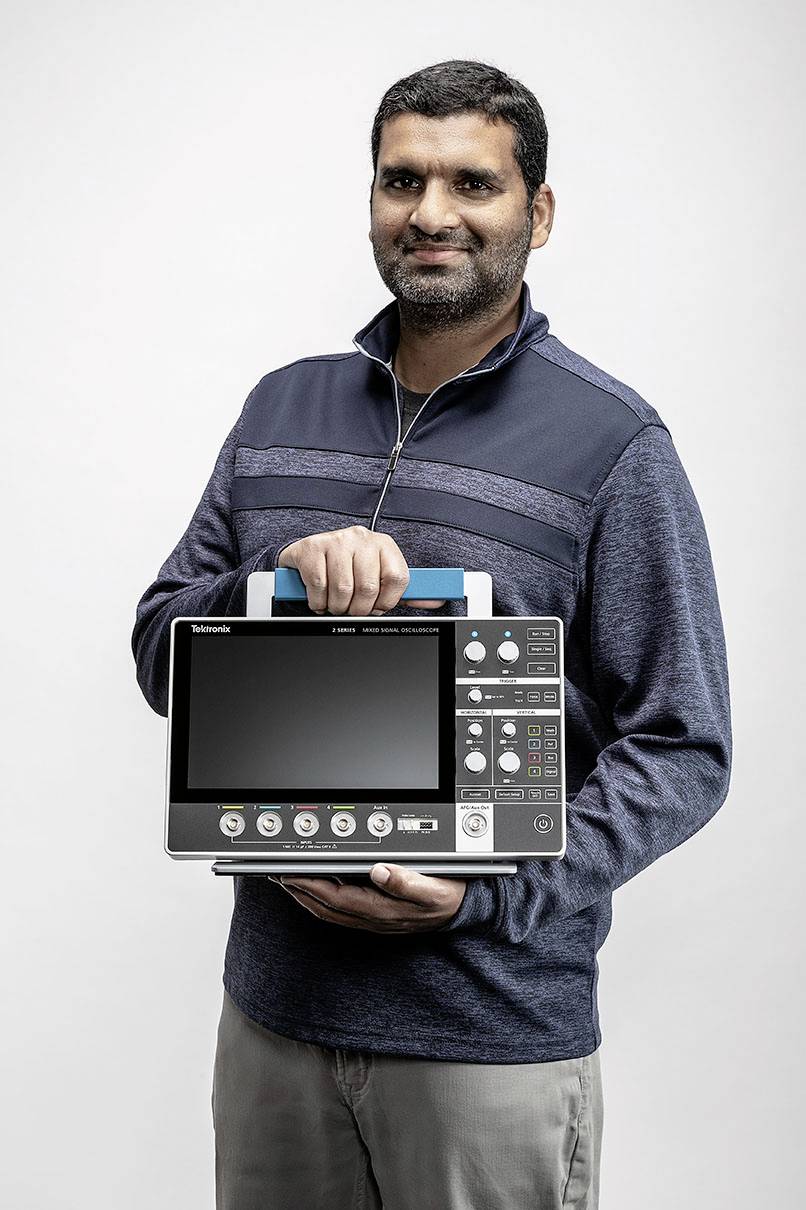 A man is holding a portable electronic device with a screen. The device has several buttons and ports on the front.