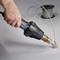A person is holding a hairdryer and directing it towards electrical cables on a work surface. A cable reel is lying in the background.