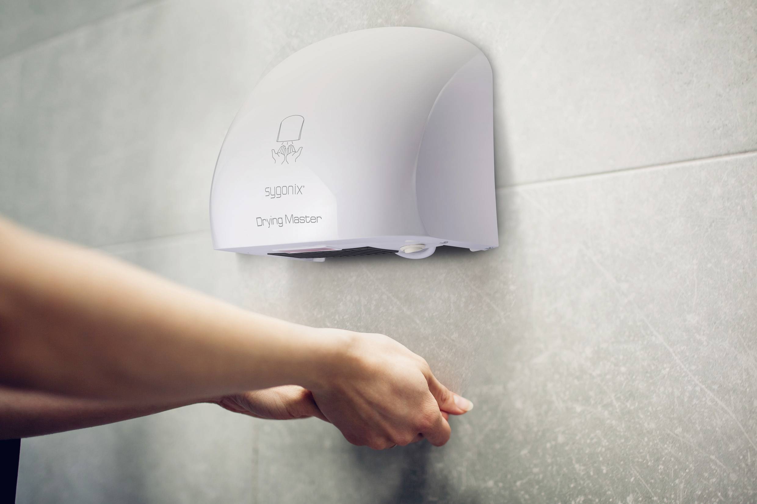 A person uses a wall-mounted hand dryer labeled 'Drying Master' by SUGOMIX, positioned in a bathroom setting with tiled walls.
