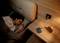 A person sleeping in bed next to a bedside table with a lamp, an alarm clock, and a charger. Cosy and tranquil atmosphere.