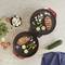 Two open electric grills with grilled meat and vegetables. Fresh ingredients such as mushrooms, tomatoes, and courgettes are laid out beside them on a table.
