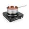 A pan of tomato soup sits on a black electric hob. The hob has a rotary dial and a red indicator light.
