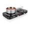 A black double hob with a pot full of tomato-coloured soup. The hob is switched on, and the pot has a handle.