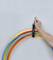A person's hand hangs a stack of colourful hula hoops on a hook on the wall.