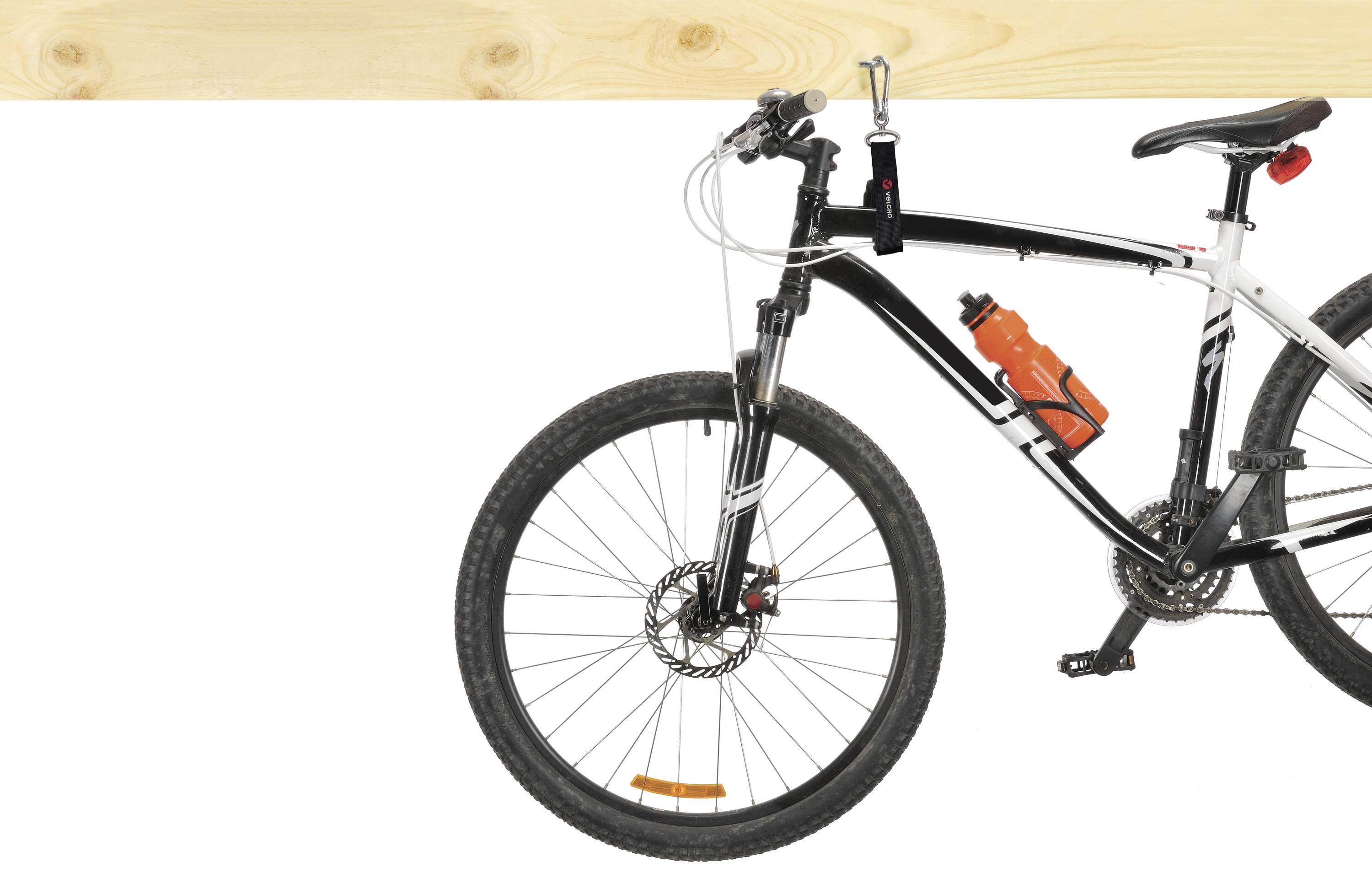 Black and white mountain bike with an orange water bottle attached to the frame, against a white background. Main focus is on the front wheel and handlebars.