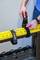 A person is attaching a device to a yellow rail using hook-and-loop fasteners.