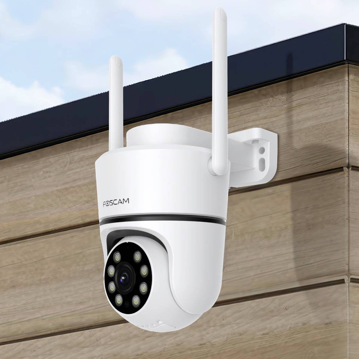 Security camera mounted on a wooden wall, with two aerials and a visible lens, facing outwards to monitor the area.
