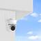 Security camera mounted on a wall, view of blue sky with clouds in the background.