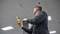 A man is holding a device that checks wireless signals in an office building. Ceiling lights and a fire alarm sign are visible.