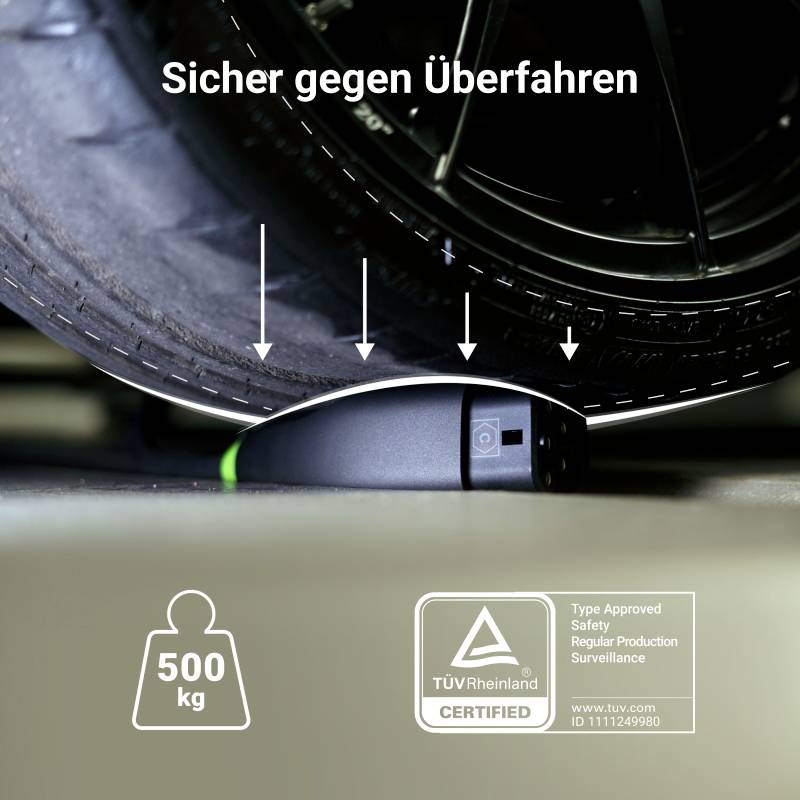 A heavy car is standing on a device marked 'Safe Against Crushing', weight symbol '500 kg', TÜV-tested.
