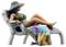 A miniature figurine of a woman in a green bikini is relaxing on a deck chair, wearing a hat and with a colourful towel.