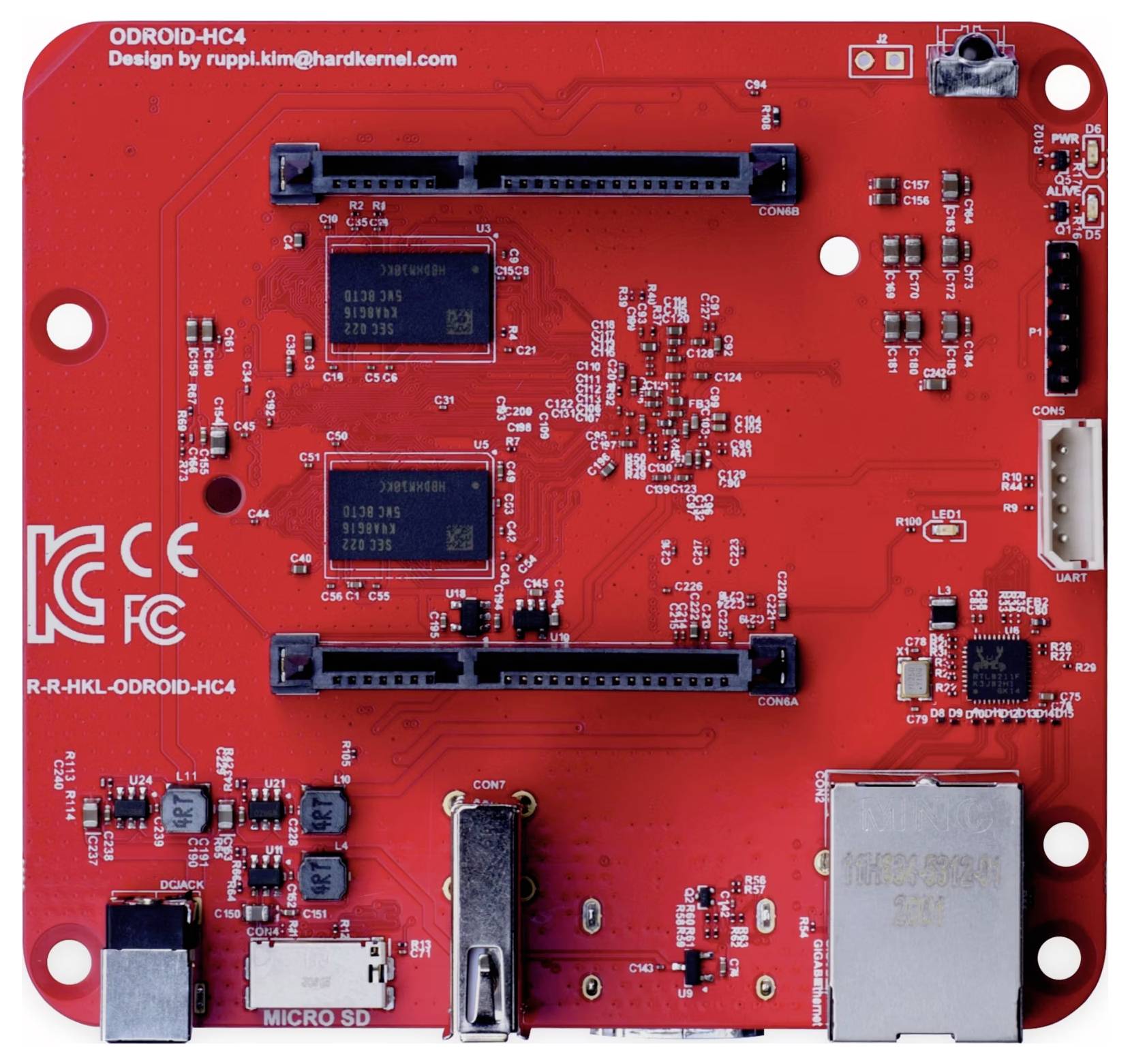 Red circuit board of a single-board computer with connectors and two memory chips, suitable for technological applications.