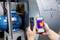 A person is using an infrared thermometer and displaying the result on a smartphone. The temperature of a large motor is being measured.
