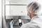 A technician is measuring air quality in a laboratory using a mobile device. He is wearing protective clothing and a hair net.