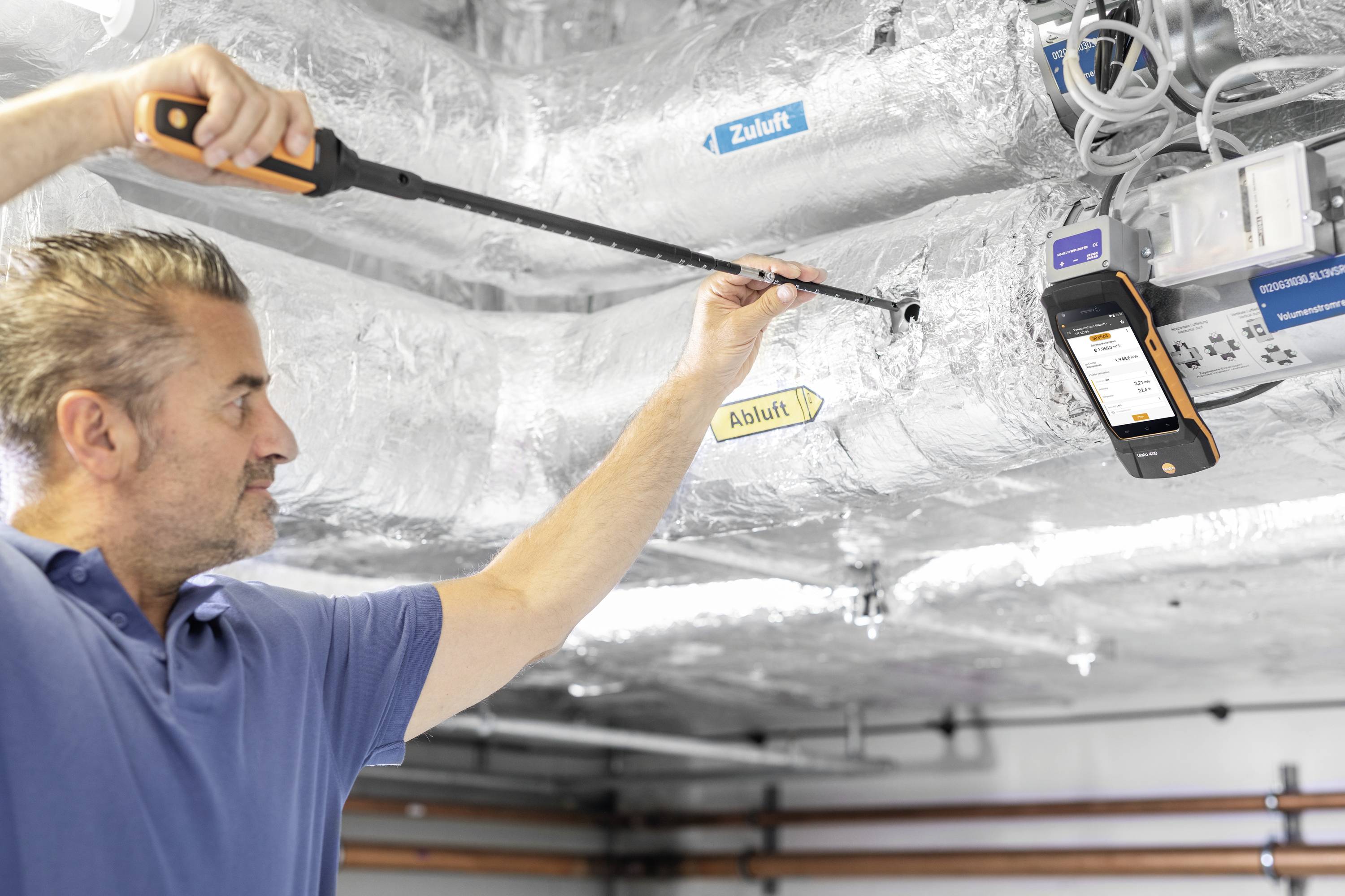'A man is measuring air velocity in a ventilated room with a measuring device.'