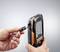 A hand is holding a portable measuring device with a display, while the other hand connects a cable plug to the device.
