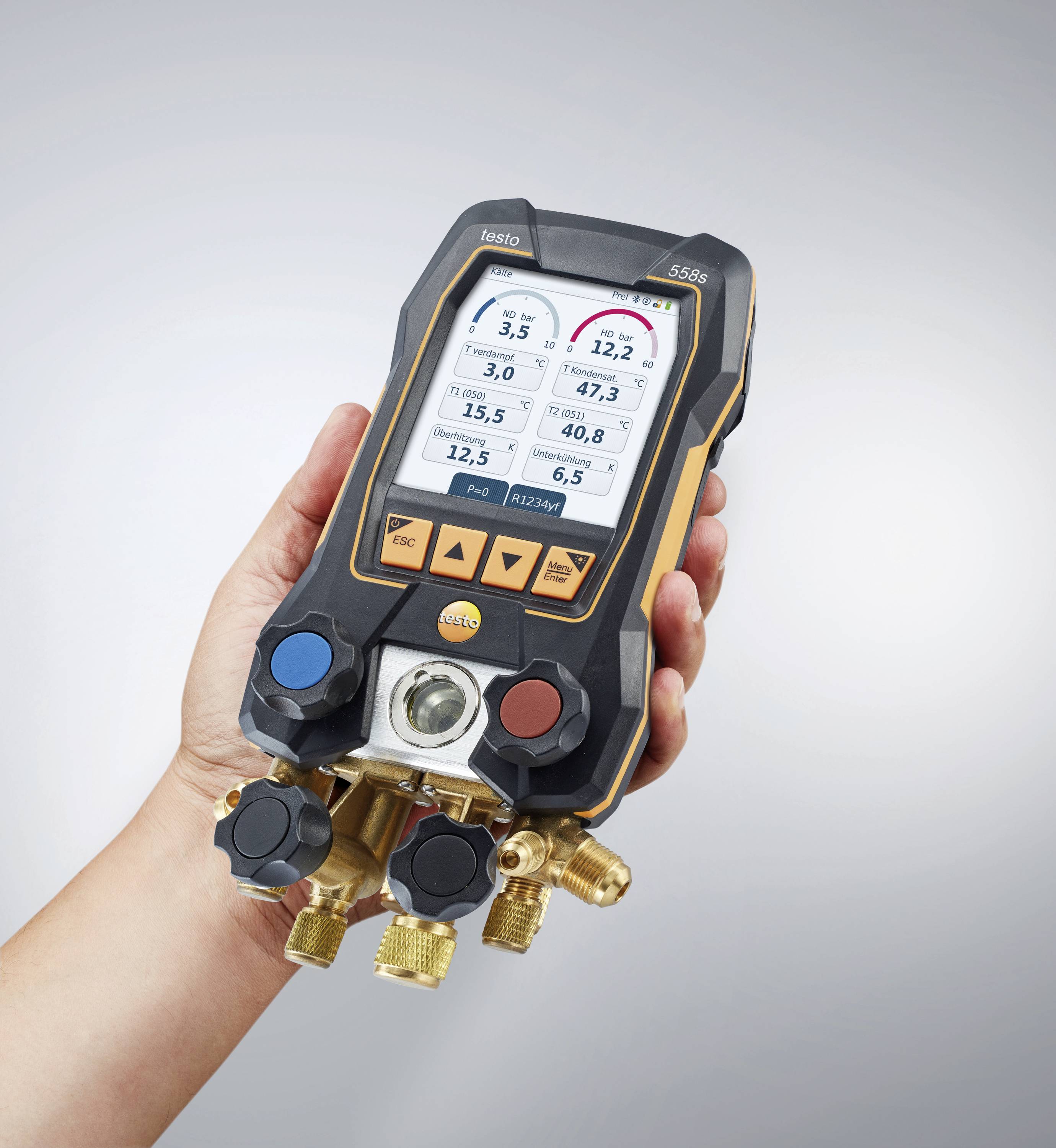 A hand is holding a digital pressure gauge with colour displays for pressure and temperature settings, showing various measurement readings.