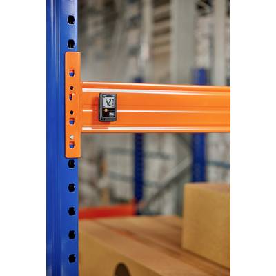 Temperature gauge on the orange shelf in a warehouse. Digital display shows 42.7 degrees. Background blurred with cardboard boxes.