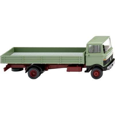 A green toy lorry with a red chassis and an open cargo area, sits on a white surface.