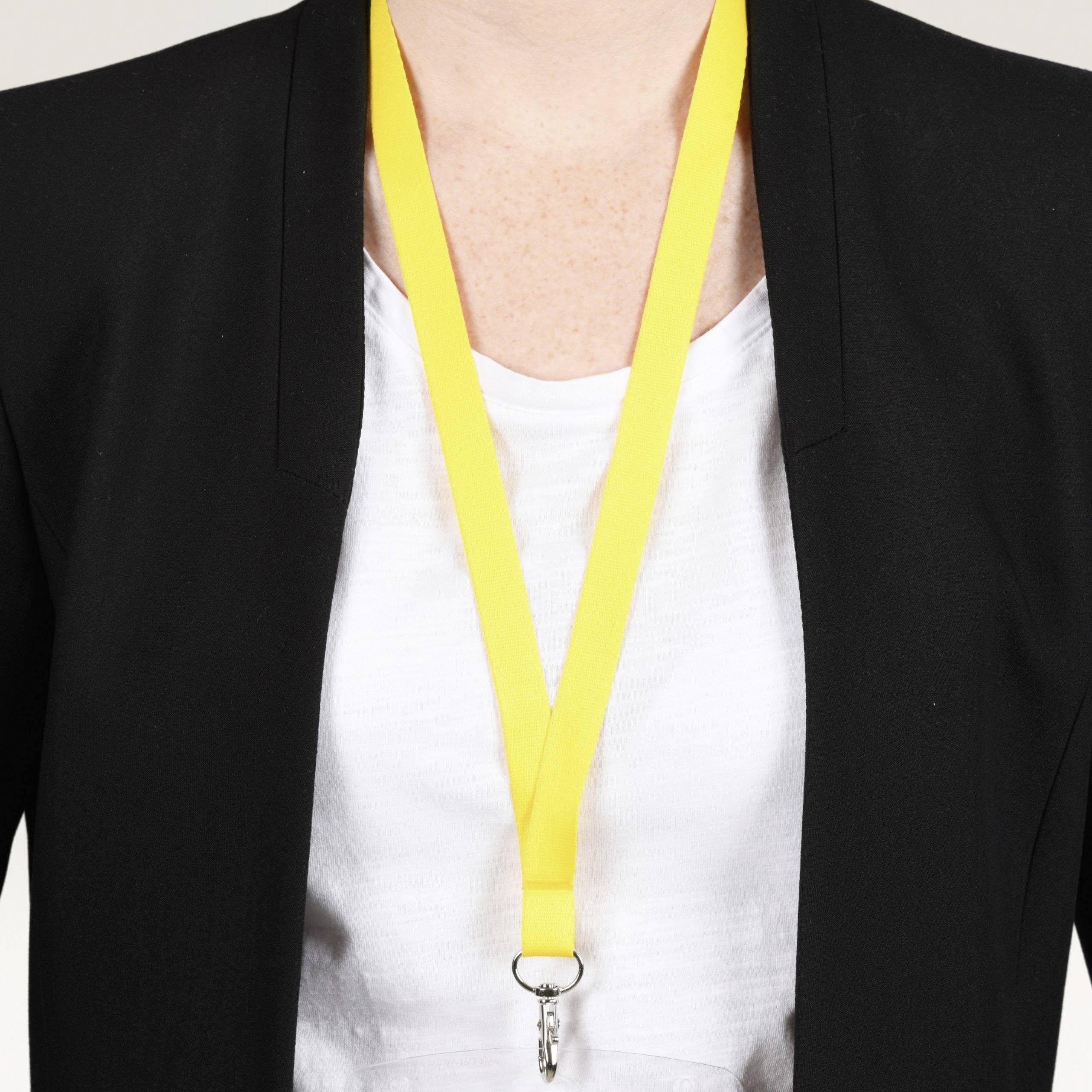 A person in a suit is wearing a yellow lanyard with a whistle around their neck.