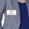 A person is wearing a name badge on a grey blazer with the inscription 'B. Carlos, Marketing Director'.