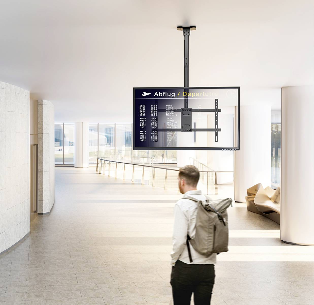 A person with a backpack is studying a departure board in a modern airport terminal.