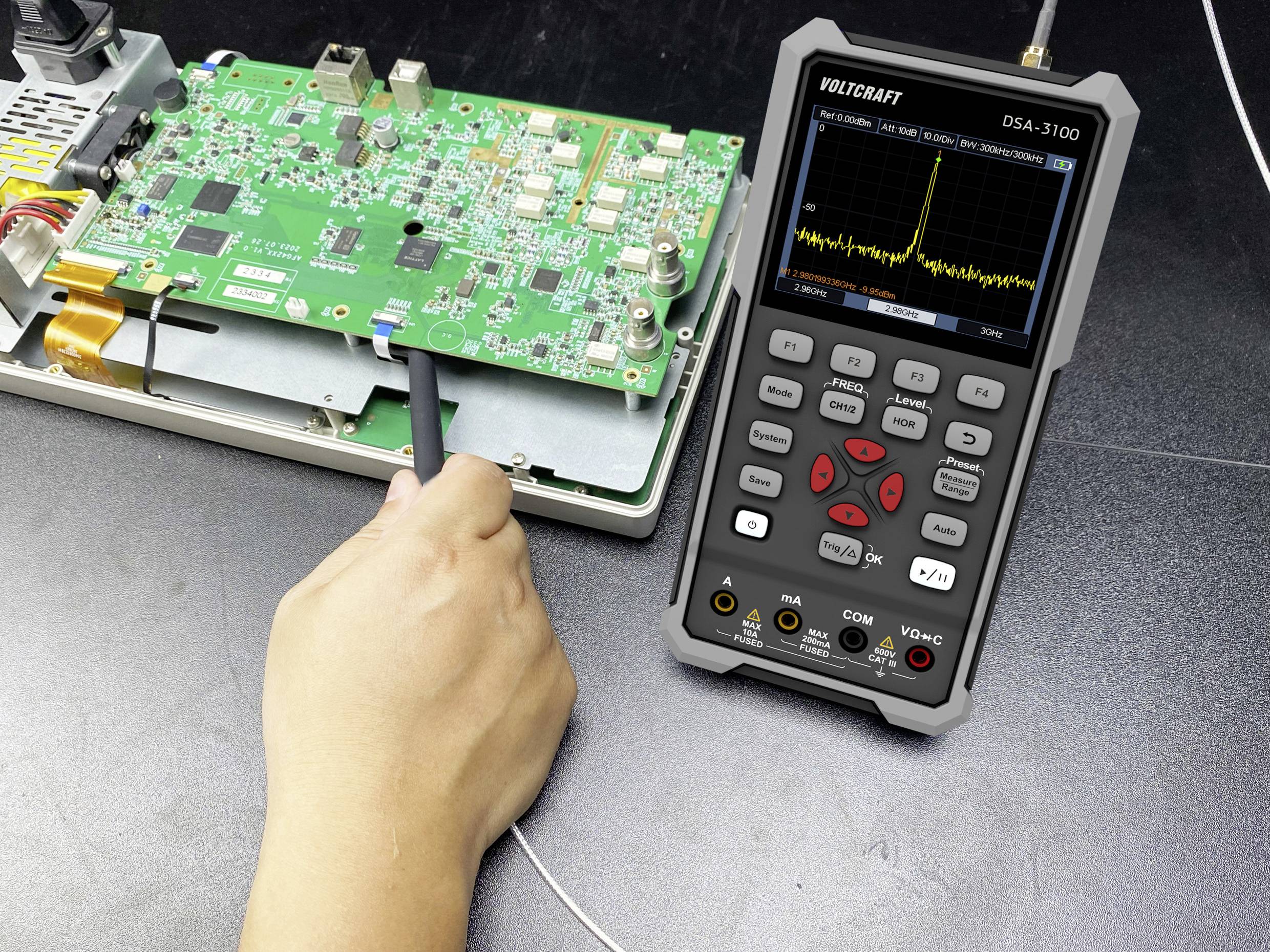 A person uses a probe on a circuit board connected to a handheld device displaying an electrical waveform, suggesting testing or diagnostics.