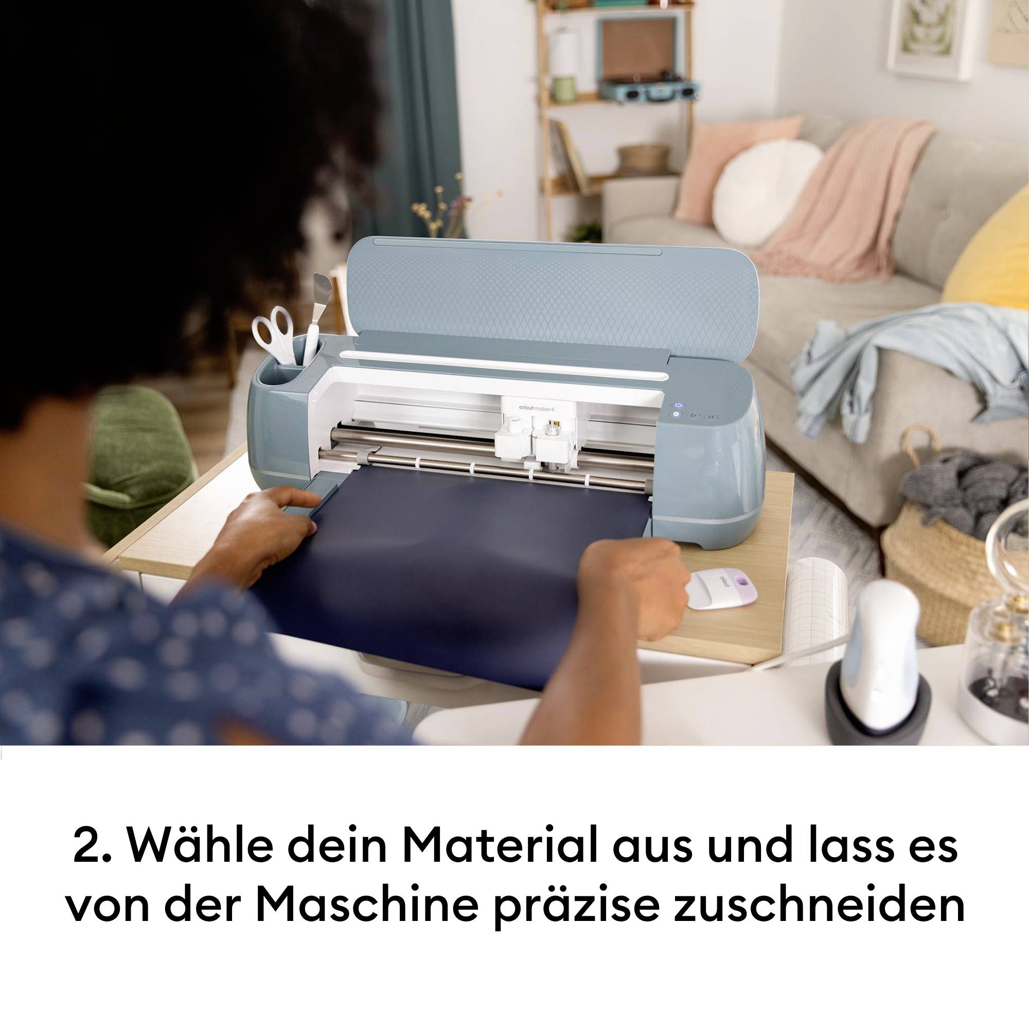 A person is placing a material into a cutting machine to cut it precisely. A sofa can be seen in the background.