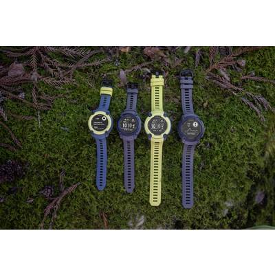 Four colourful outdoor smartwatches on moss-covered ground, each displaying different screens.