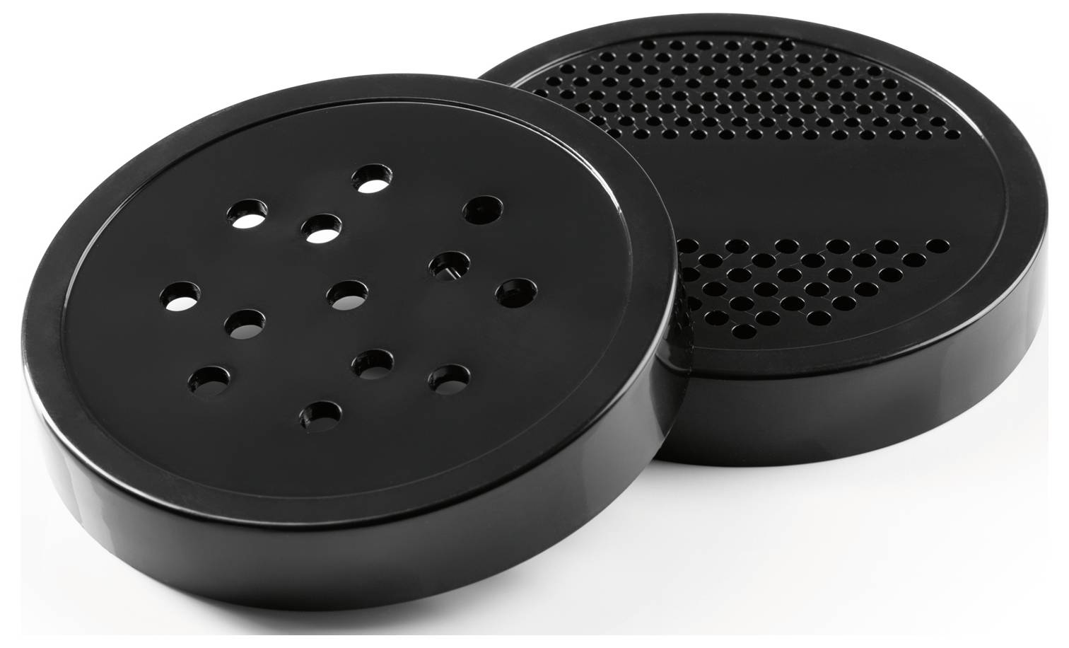 Two round, black lids with perforated patterns, one with larger holes and the other with smaller holes. They are slightly tilted in relation to each other.