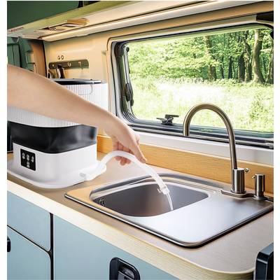 A person is filling water into a sink in a motorhome. A compact device with a hose is situated on the worktop.