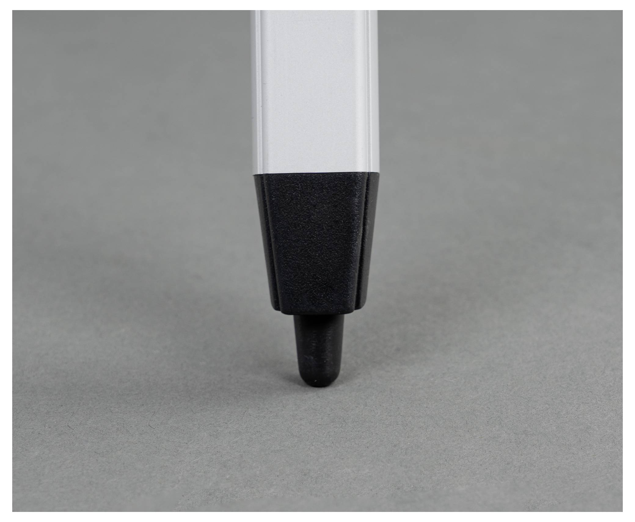 A chrome-plated pen is lying on a grey surface.