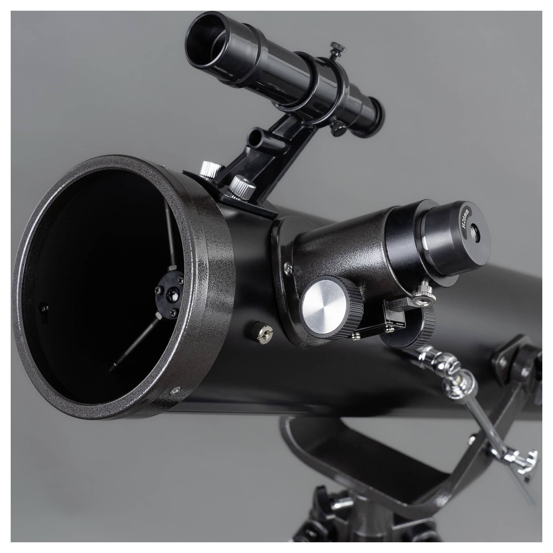 'A black telescope with a finder and focusing wheel, positioned at a slightly tilted angle, against a grey background.'